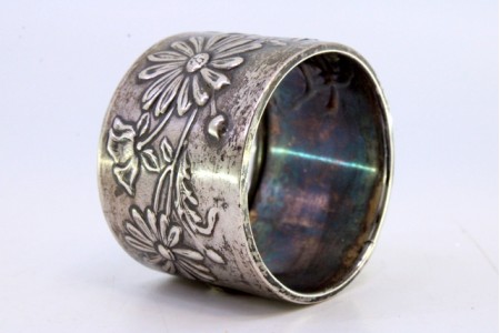 Argola de guardanapo em prata com motivos florais relevados.